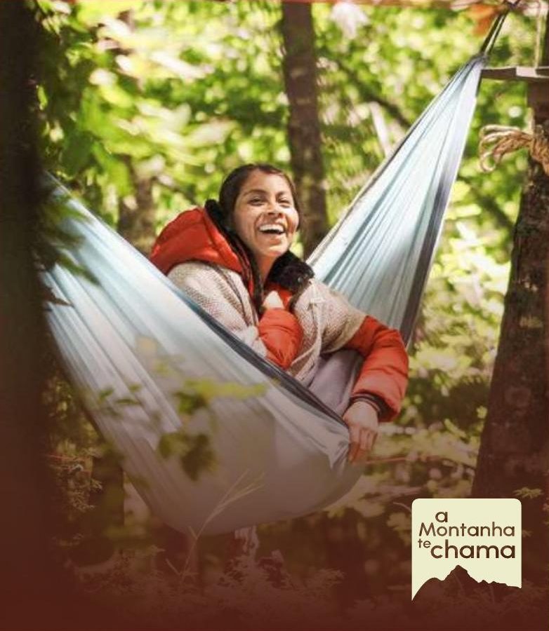 Participante rindo em uma rede entre árvores na floresta
